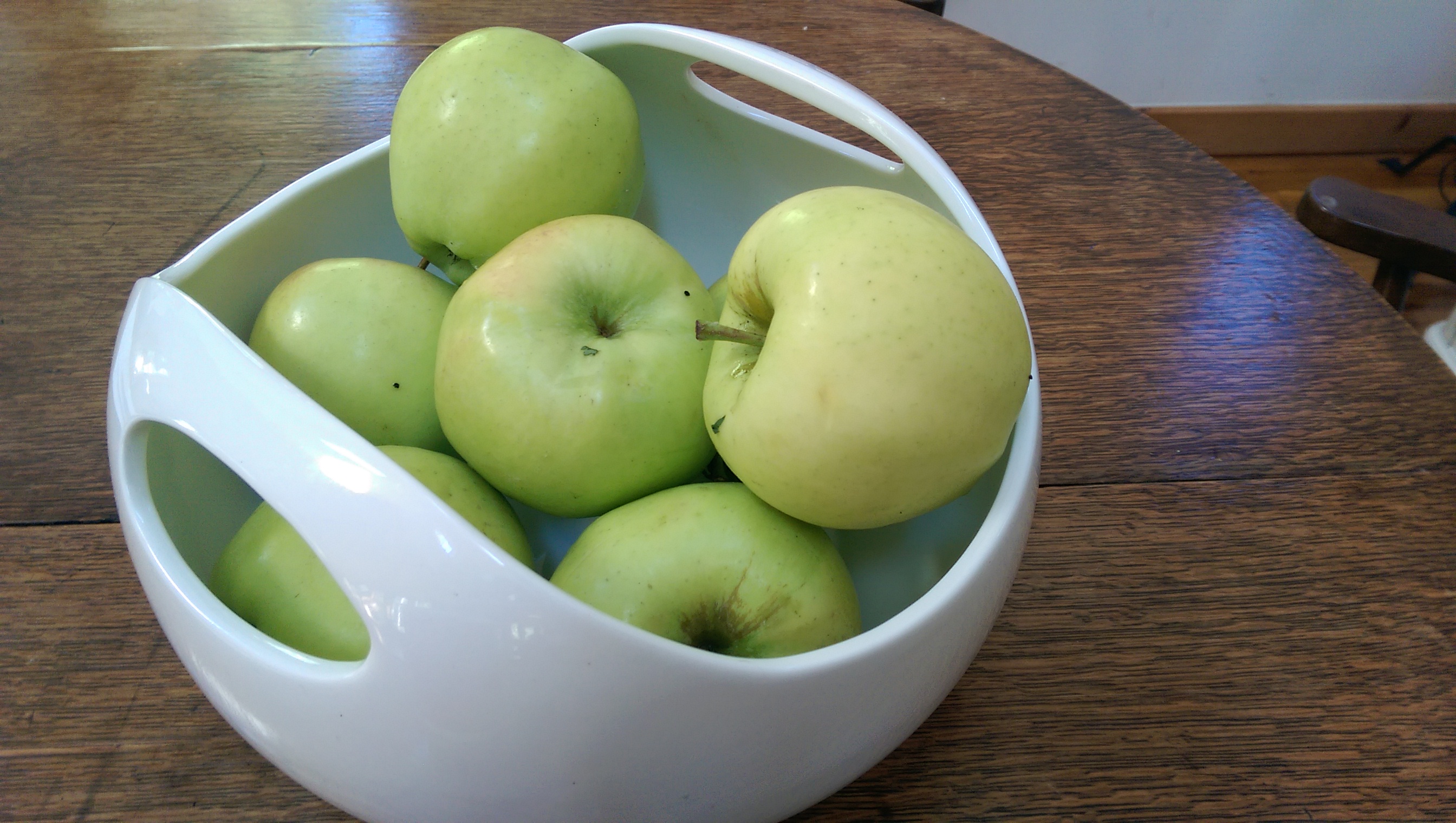 white bowl filled with green apples